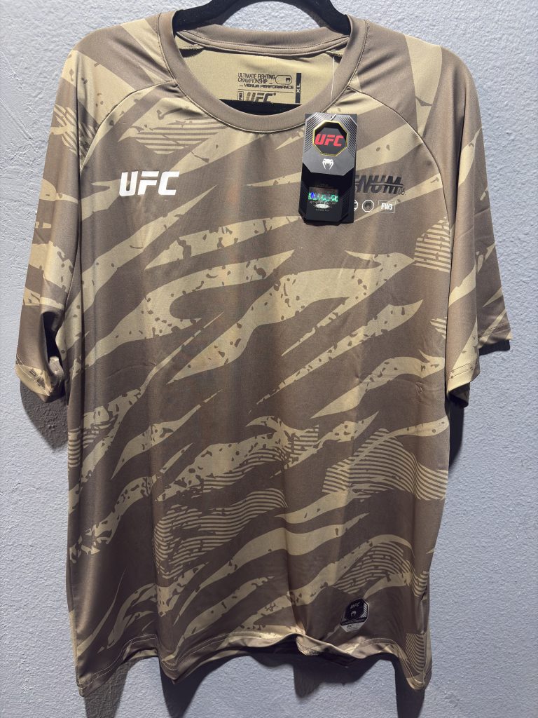 UFC x Venum Authentic Fight Week Walkout Jersey in Desert Camo showing the front chest logo, neck label, and hanging tags in size XL.