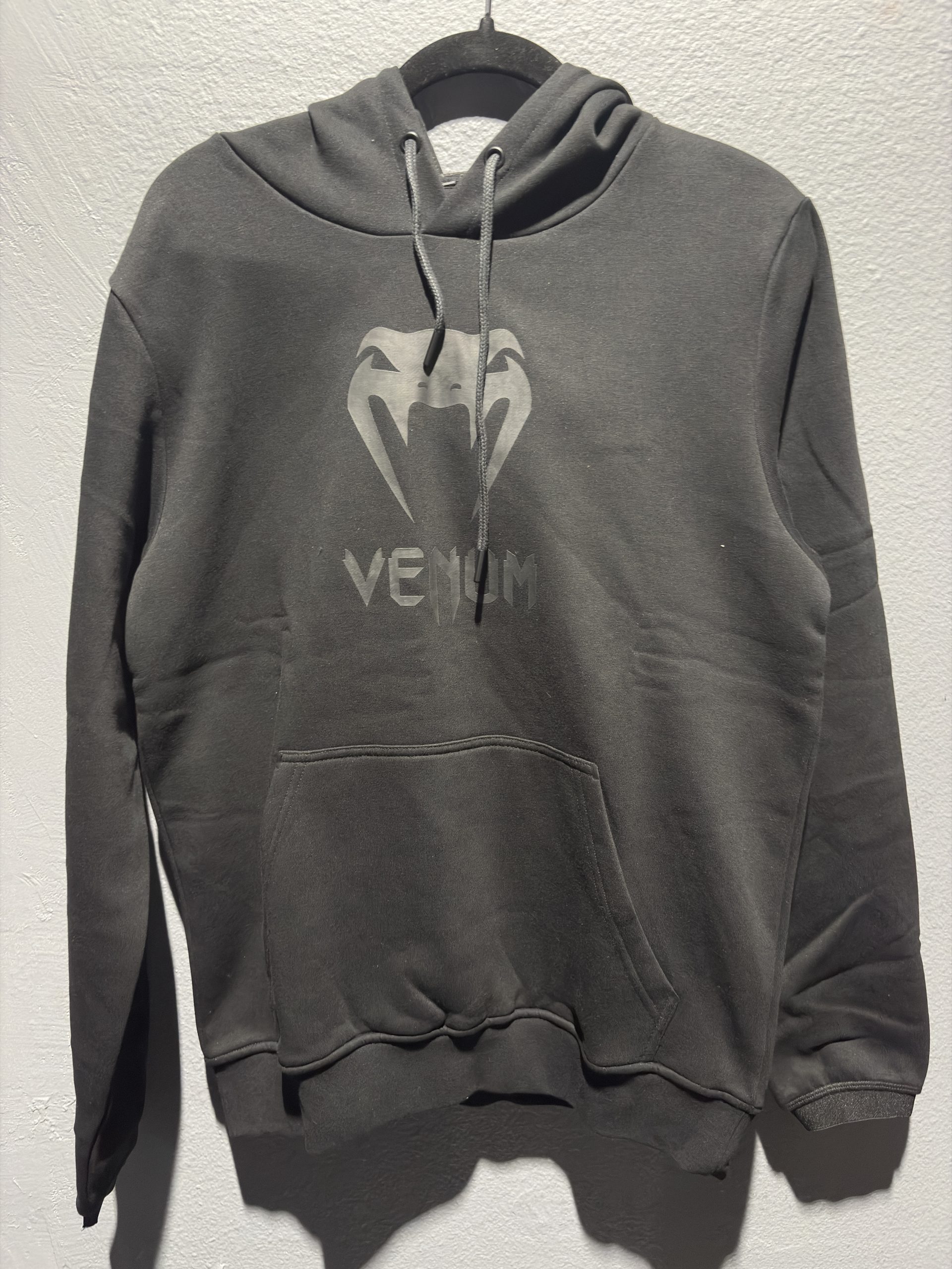 Venum Classic Hoodie in Black/Black showing the chest logo and retail tag in size M.