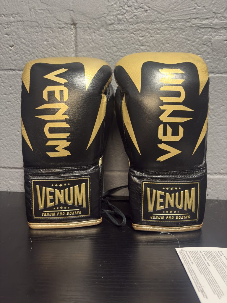 Venum Hammer Pro Boxing Gloves in Black and Gold shown with their retail box and size label in 8oz.