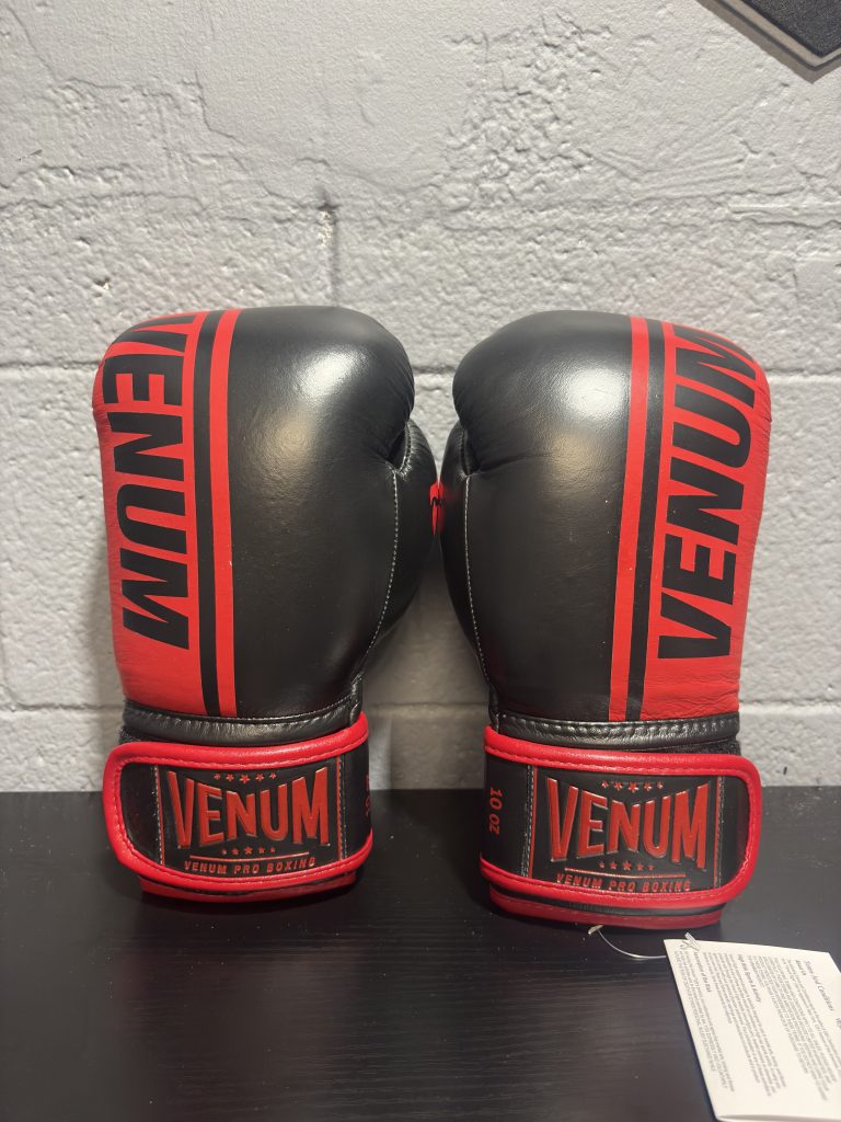 Venum Shield Pro Boxing Gloves in Black and Red shown with their retail box and size label in 10oz.