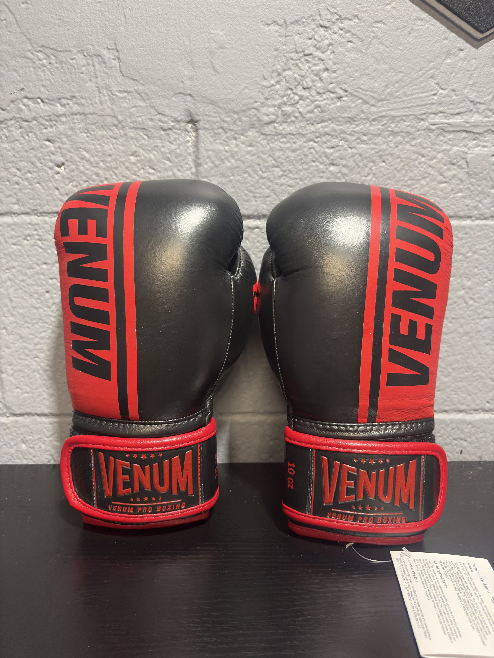 Venum Shield Pro Boxing Gloves in Black and Red shown with their retail box and size label in 10oz.
