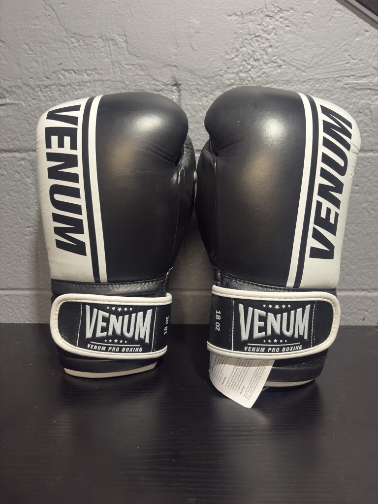 Venum Shield Pro Boxing Gloves in Black and White shown with their retail box and size label in 18oz.