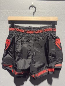 Venum Parachute Muay Thai Shorts in Black and Red showing the elastic waistband, brand tag, and side logo in size L.