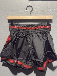 Venum Parachute Muay Thai Shorts in Black and Red showing the elastic waistband, brand tag, and side logo in size M.