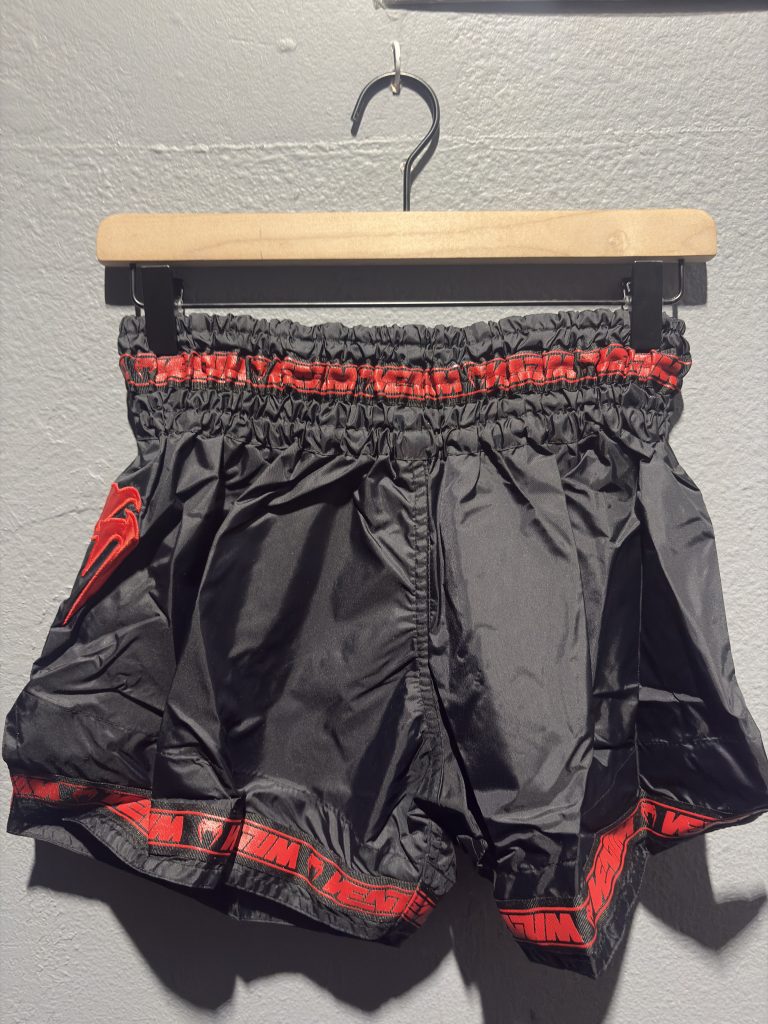 Venum Parachute Muay Thai Shorts in Black and Red showing the elastic waistband, brand tag, and side logo in size M.
