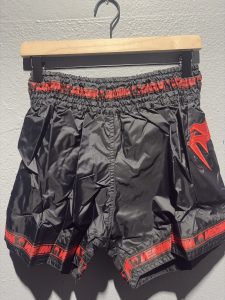 Venum Parachute Muay Thai Shorts in Black and Red showing the elastic waistband, brand tag, and side logo in size XL.