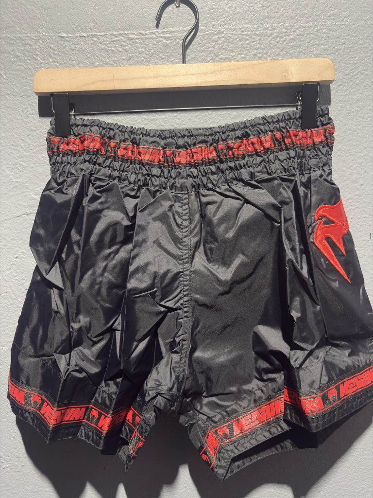 Venum Parachute Muay Thai Shorts in Black and Red showing the elastic waistband, brand tag, and side logo in size XL.