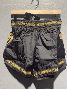 Venum Parachute Muay Thai Shorts in Black and Gold showing the elastic waistband, brand tag, and side logo in size XL.