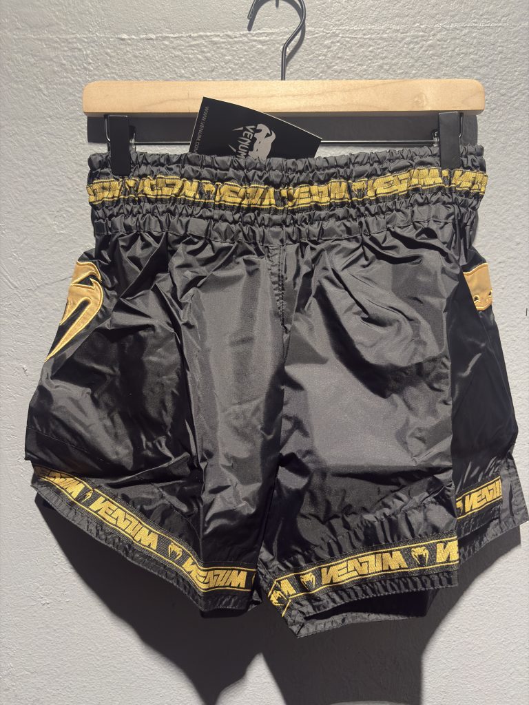 Venum Parachute Muay Thai Shorts in Black and Gold showing the elastic waistband, brand tag, and side logo in size XL.