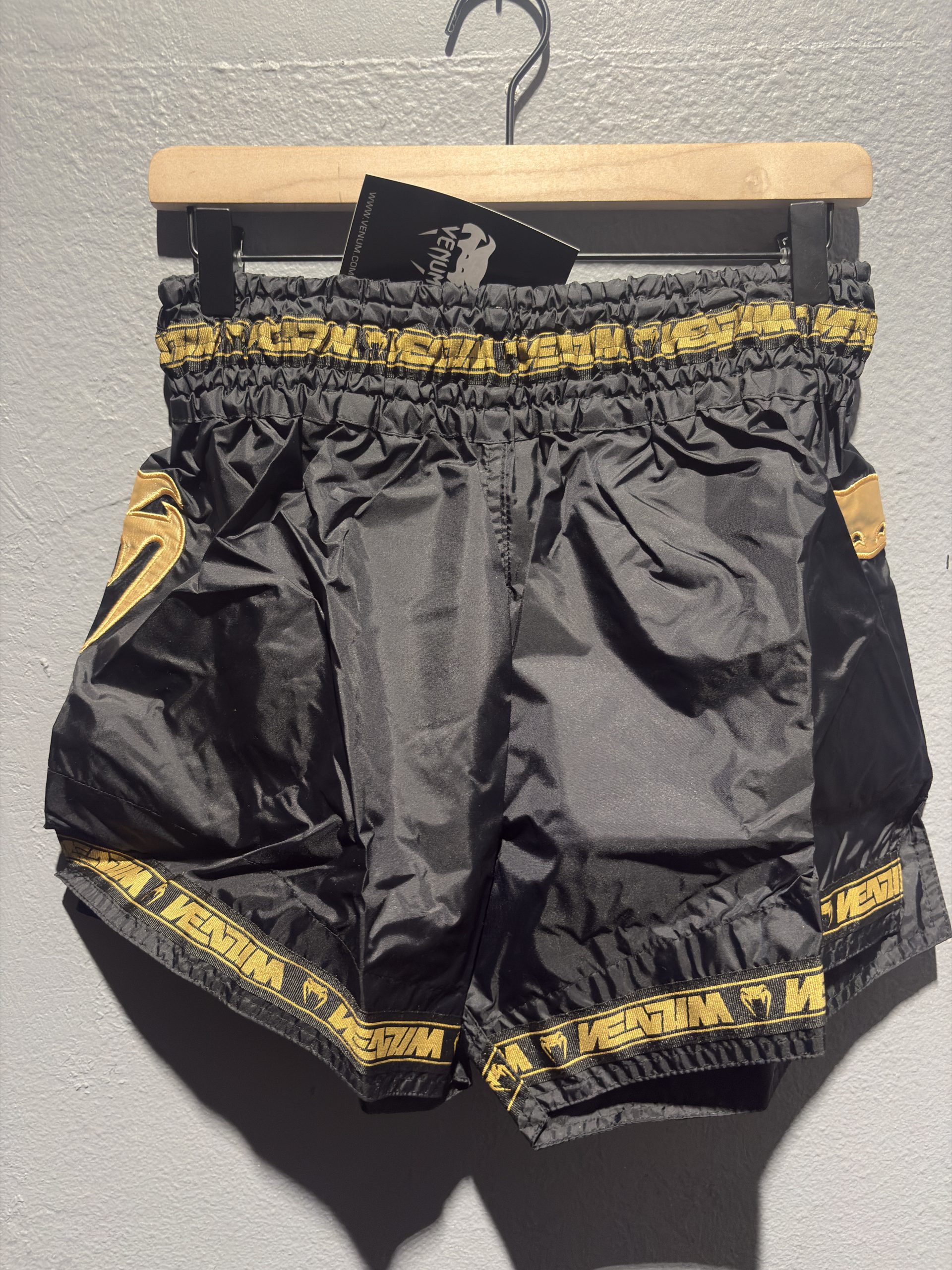 Venum Parachute Muay Thai Shorts in Black and Gold showing the elastic waistband, brand tag, and side logo in size XL.