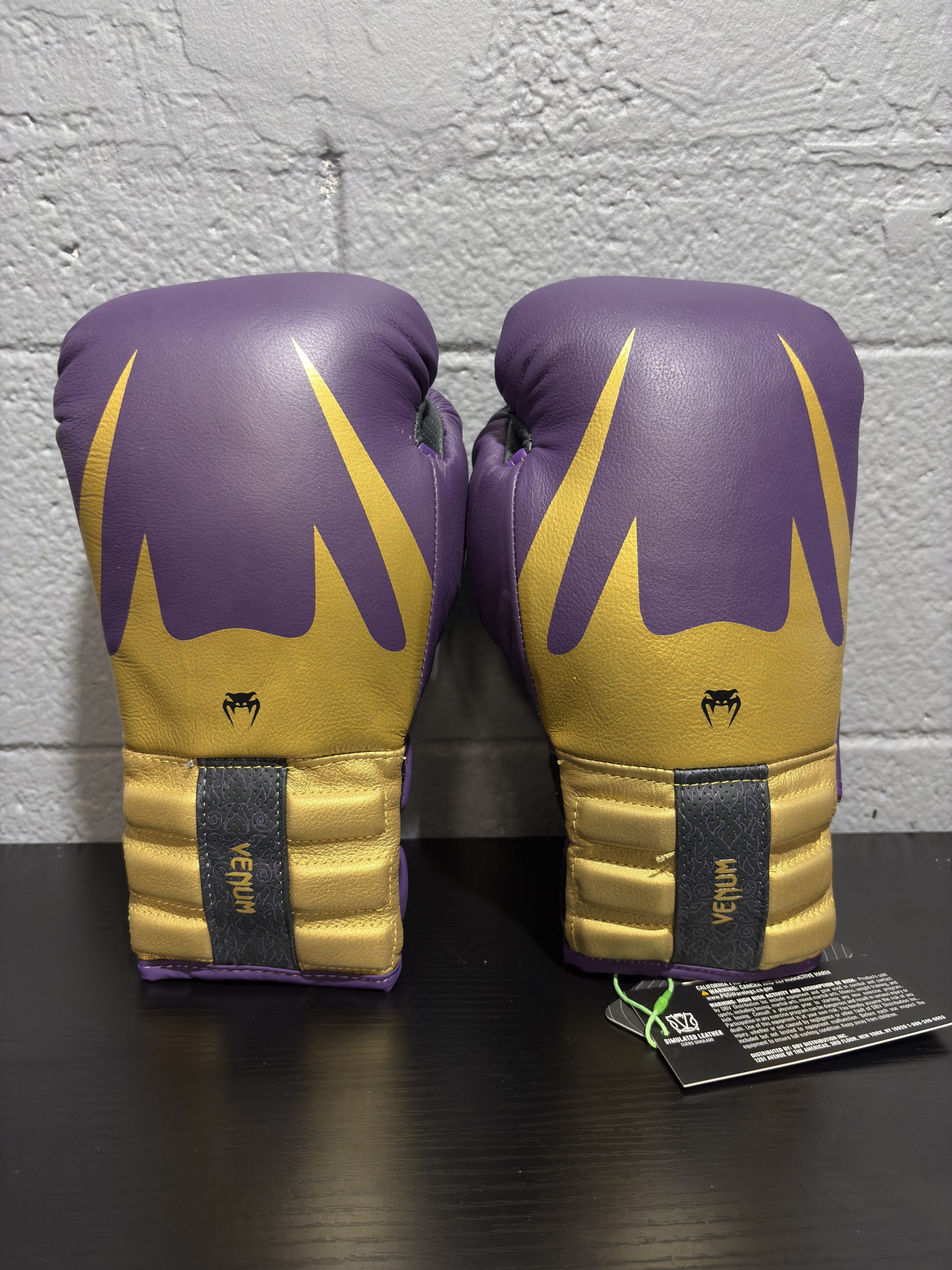 Venum Reverso Boxing Gloves in Dark Purple and Gold showing the fist design, cuff details, and hanging retail tag in size 12oz.