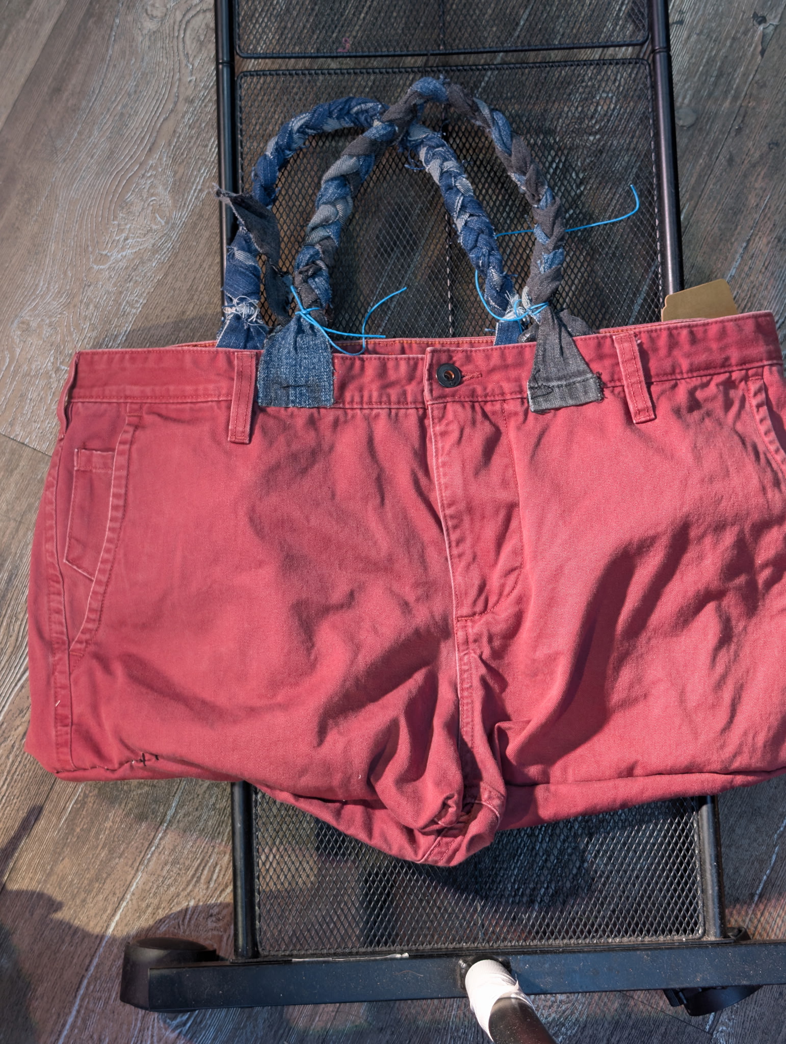 Upcycled Dockers pants tote bag in red maroon showing the front waistband, braided denim handles, and back patch details.