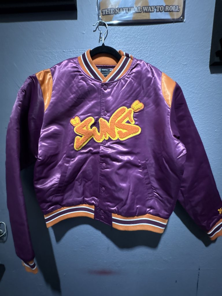 Bleacher Report The Residency Phoenix Suns satin bomber jacket in purple and orange showing the front chest embroidery, back logo, and size M tag.