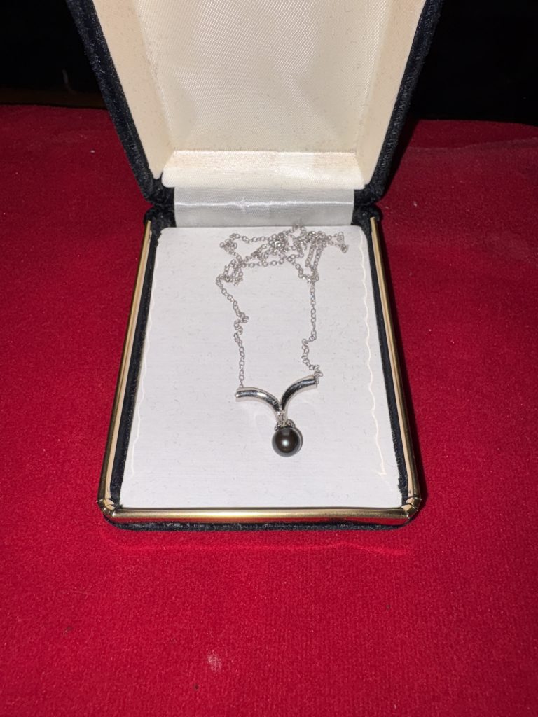 Vintage silver-tone black pearl pendant necklace with curved V bail inside a hinged presentation box.